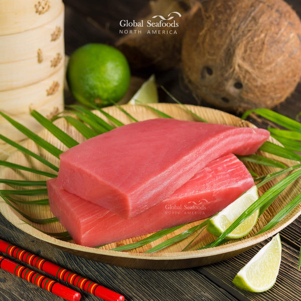 Two yellowfin tuna saku blocks on a plate with lime wedges