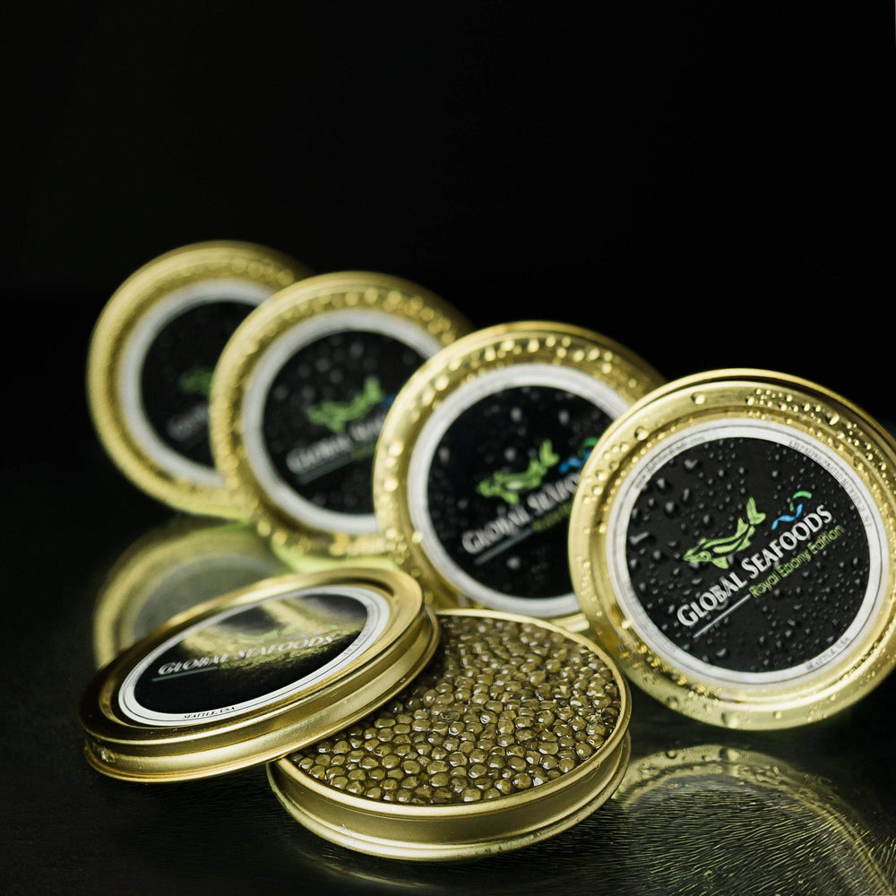 Sturgeon caviar sampler with four closed tins side by side and one open tin showing glossy black caviar, with the lid resting on top, all set against a black background for a luxurious presentation