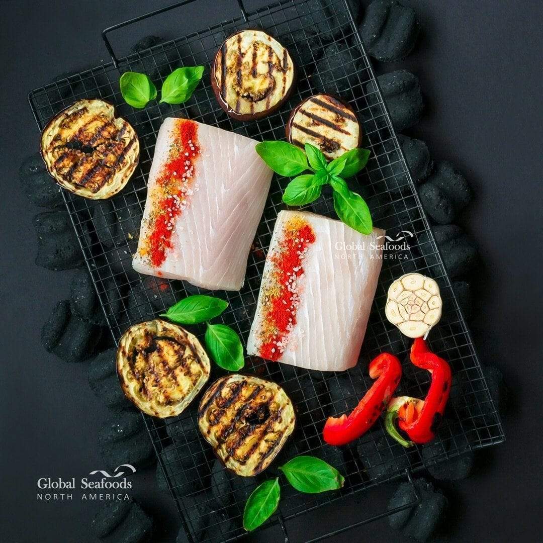 Raw mahi mahi portions on a rack with spices and grilled vegetables