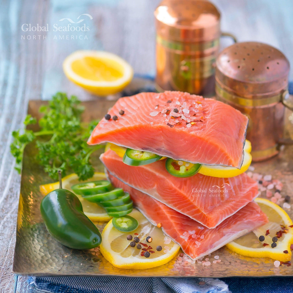 Three king salmon portions stacked with lemon slices and green chili