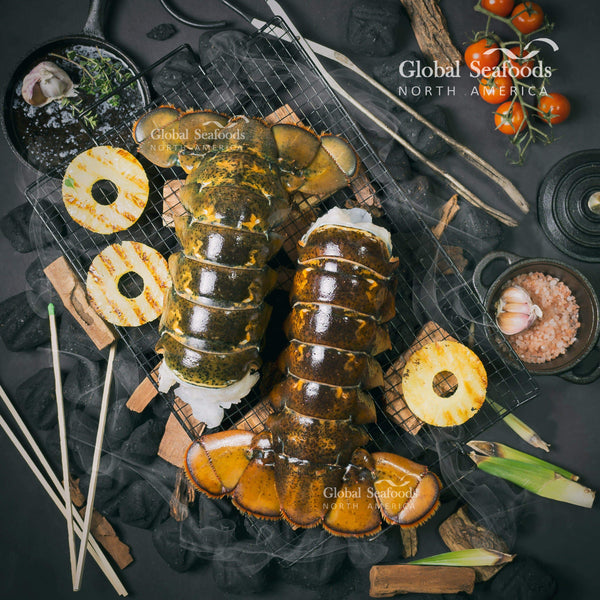 Lobster tails with pineapple slices and grilling utensils
