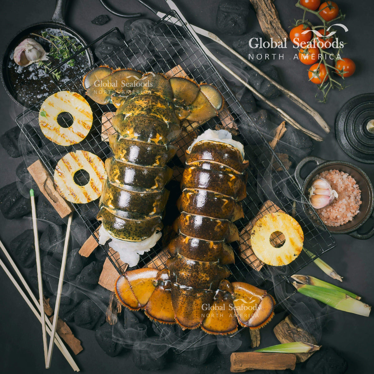 Lobster tails with pineapple slices and grilling utensils