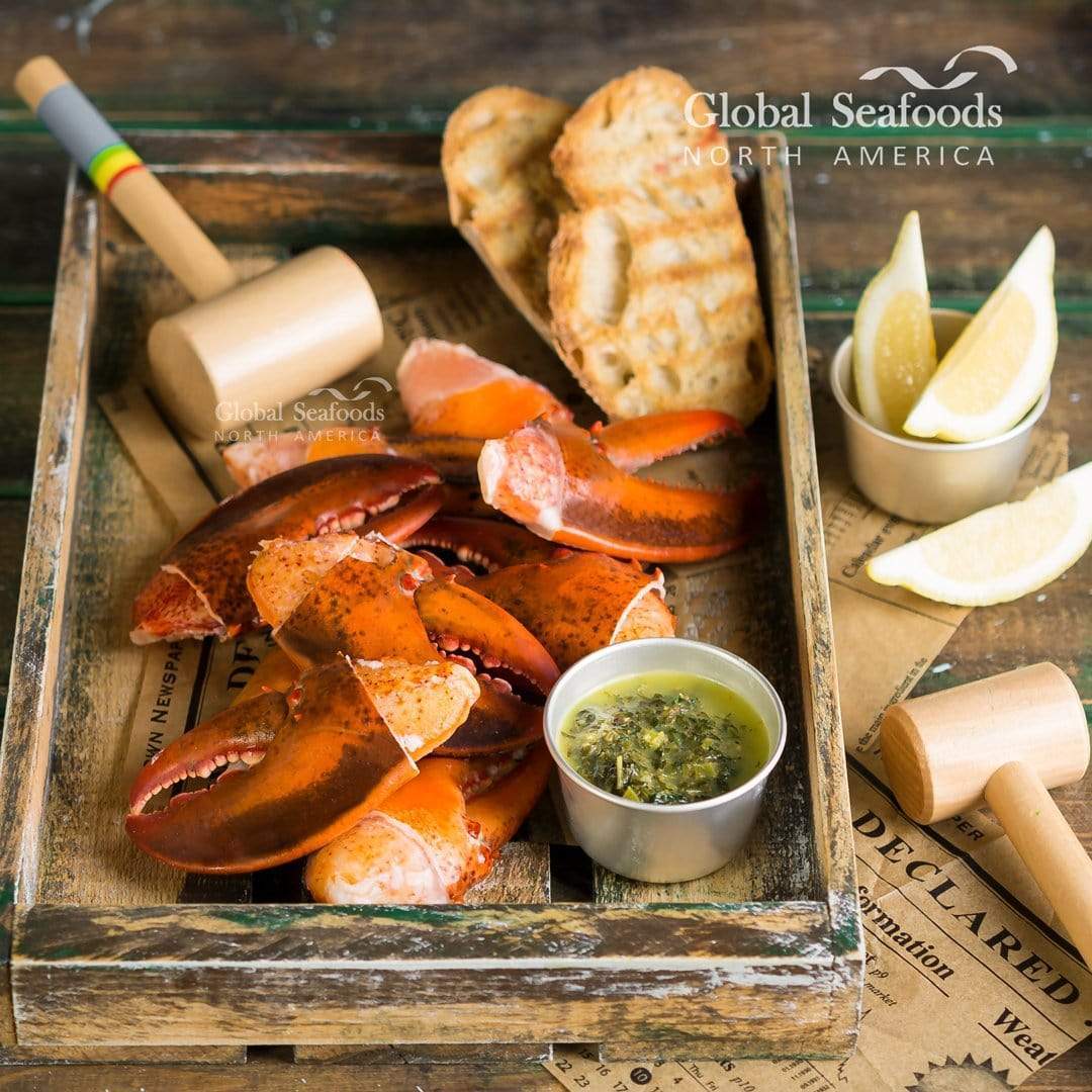 Lobster claws on a wooden tray with a mallet and sauce