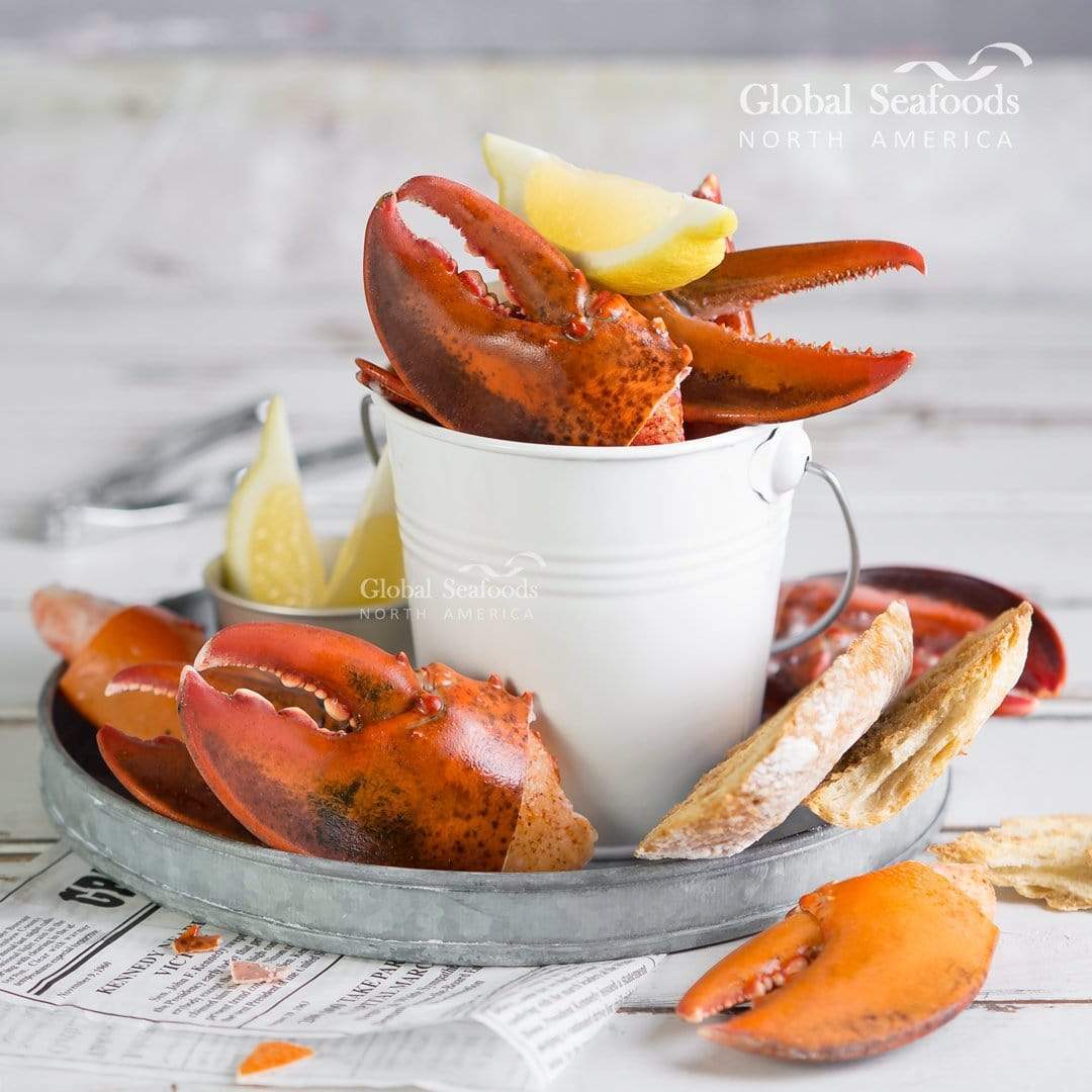 Lobster claws in a metal basket with toast and lemon