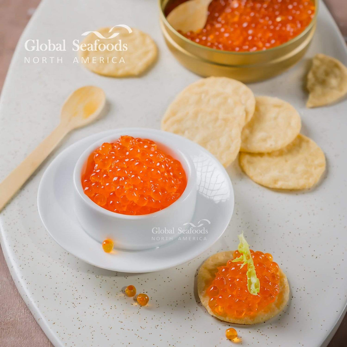 Close-up of trout roe in a white bowl and on a cracker, with plain crackers and an open tin behind
