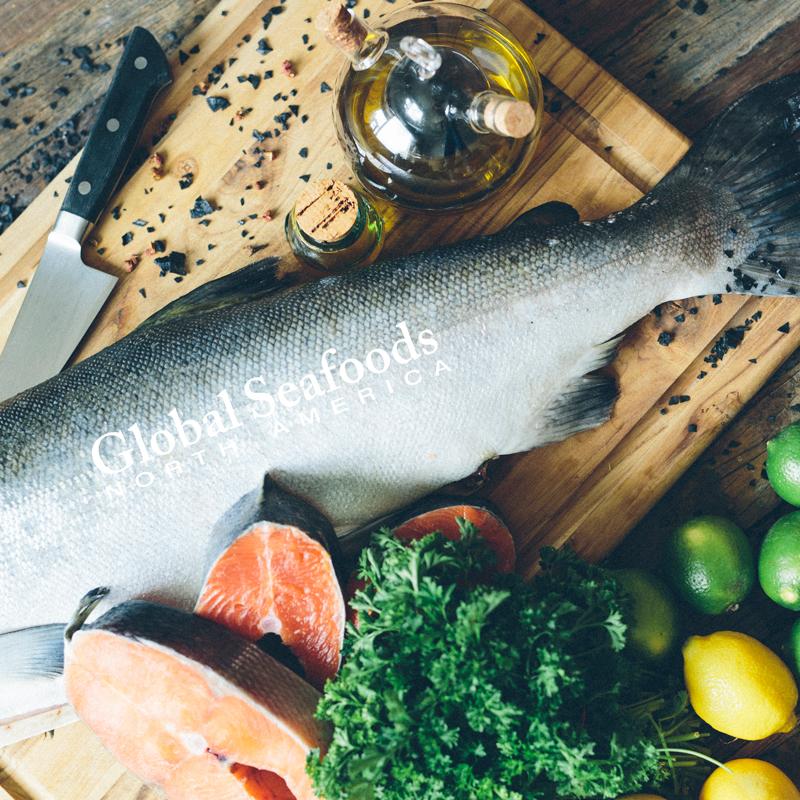 Overhead view of headless coho salmon and cut steaks with lemon and olive oil