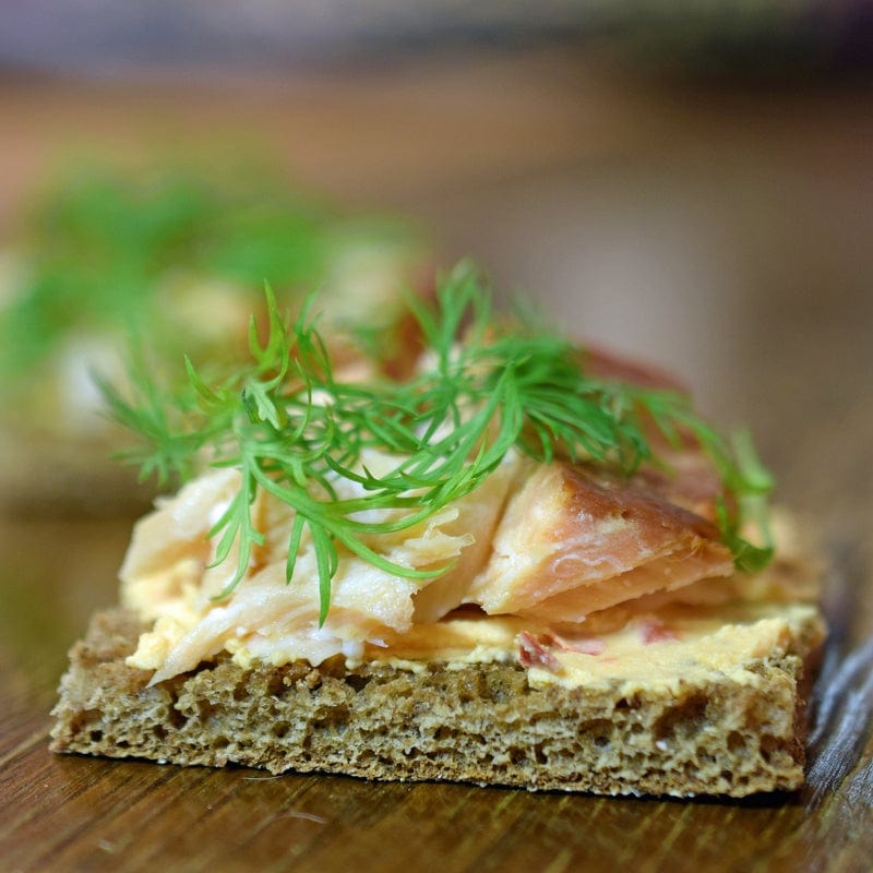 Hot premium smoked sablefish (black cod) served on slices of bread, showcasing its rich, flaky texture and deep smoky flavor for a gourmet seafood snack