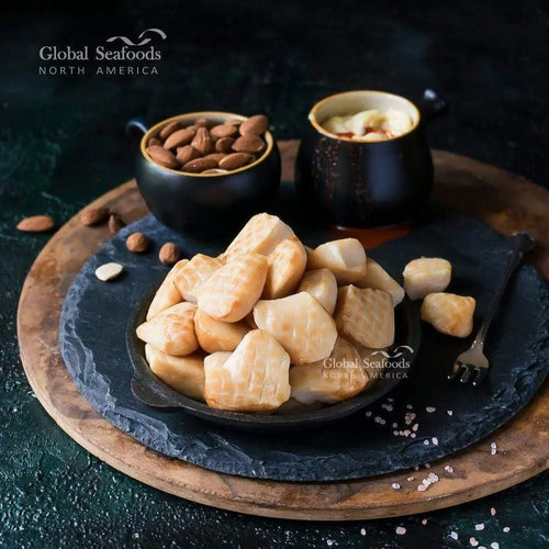 Smoked Weathervane scallops neatly arranged on a wooden board, showcasing their golden-brown smoked exterior.