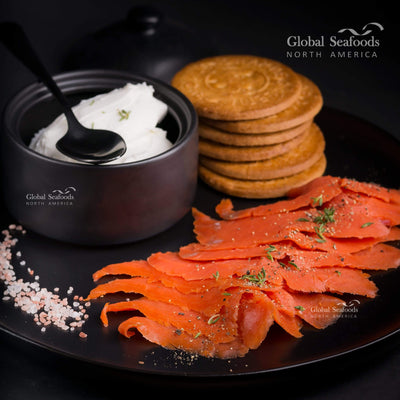 Sockeye salmon sugar-free Nova lox served on a black plate with crackers and a dollop of sour cream, sliced for an elegant, low-sugar seafood appetizer