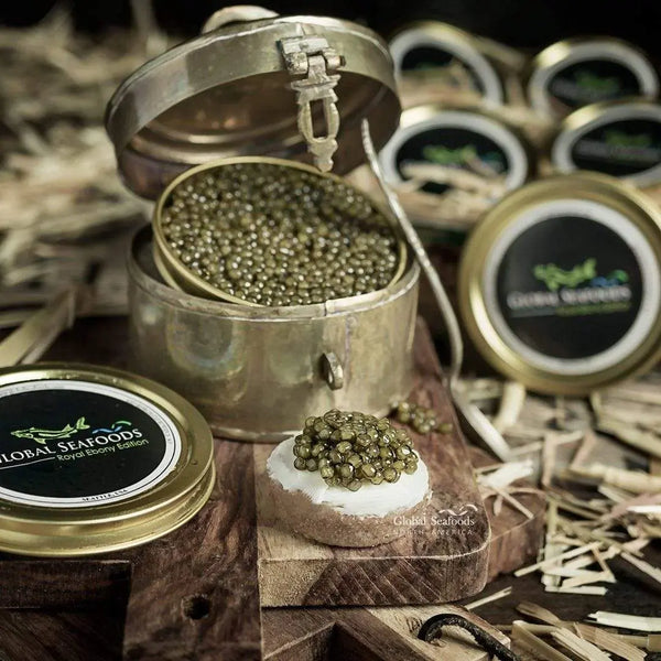 Open tin of Ossetra caviar in a metal presentation case beside a bread canapé topped with caviar