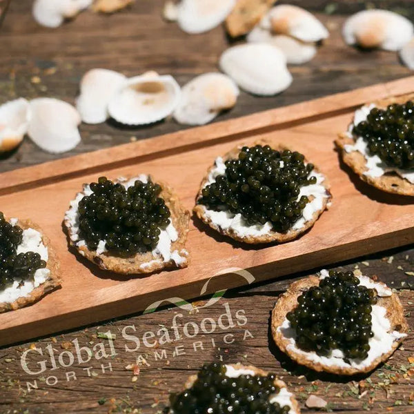 Paddlefish caviar on cream-topped crackers arranged on a wooden serving board and rustic table