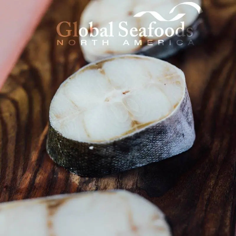 Close-up of sablefish steaks on a wooden board.