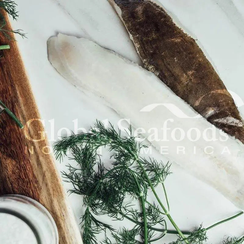 Skin-on Dover sole fillets on a wooden board with dill