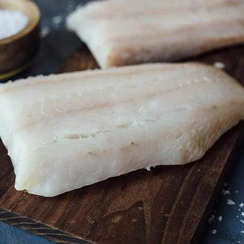 Close-up of raw lingcod fillets on a wooden board