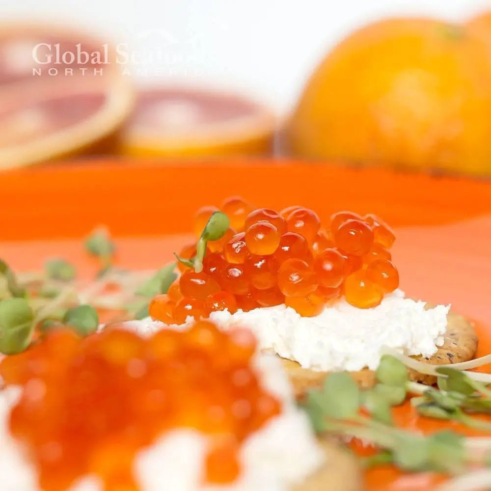Close-up of chum salmon roe on a cream cheese cracker with microgreens
