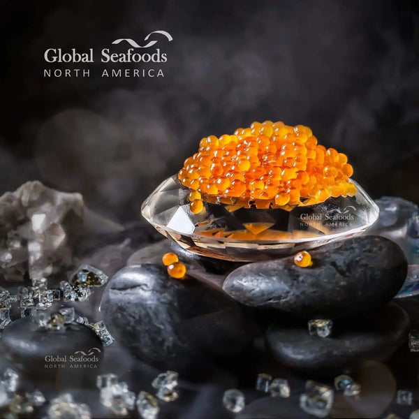 Chum salmon roe served in a crystal bowl placed on black rocks, with decorative crystals around it, highlighting the vibrant orange pearls in a luxurious presentation