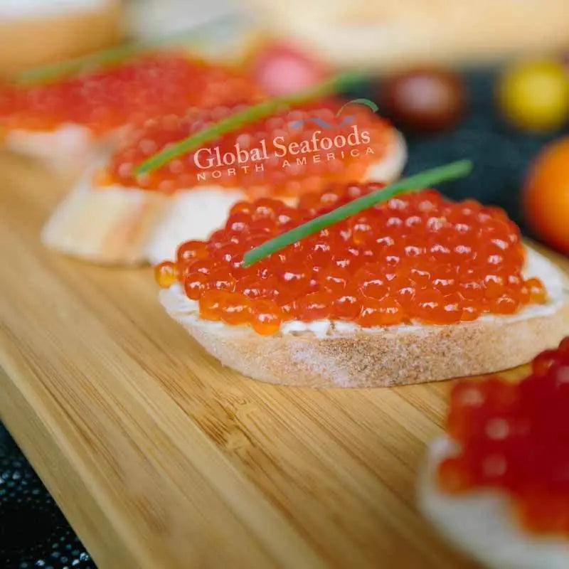 Close-up of pink salmon roe on a baguette slice topped with chives