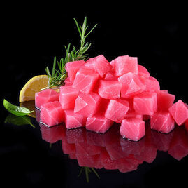 Ahi tuna cubes cut for poke, arranged in uniform cubes on a dark background surface, highlighting their deep red color and fresh quality